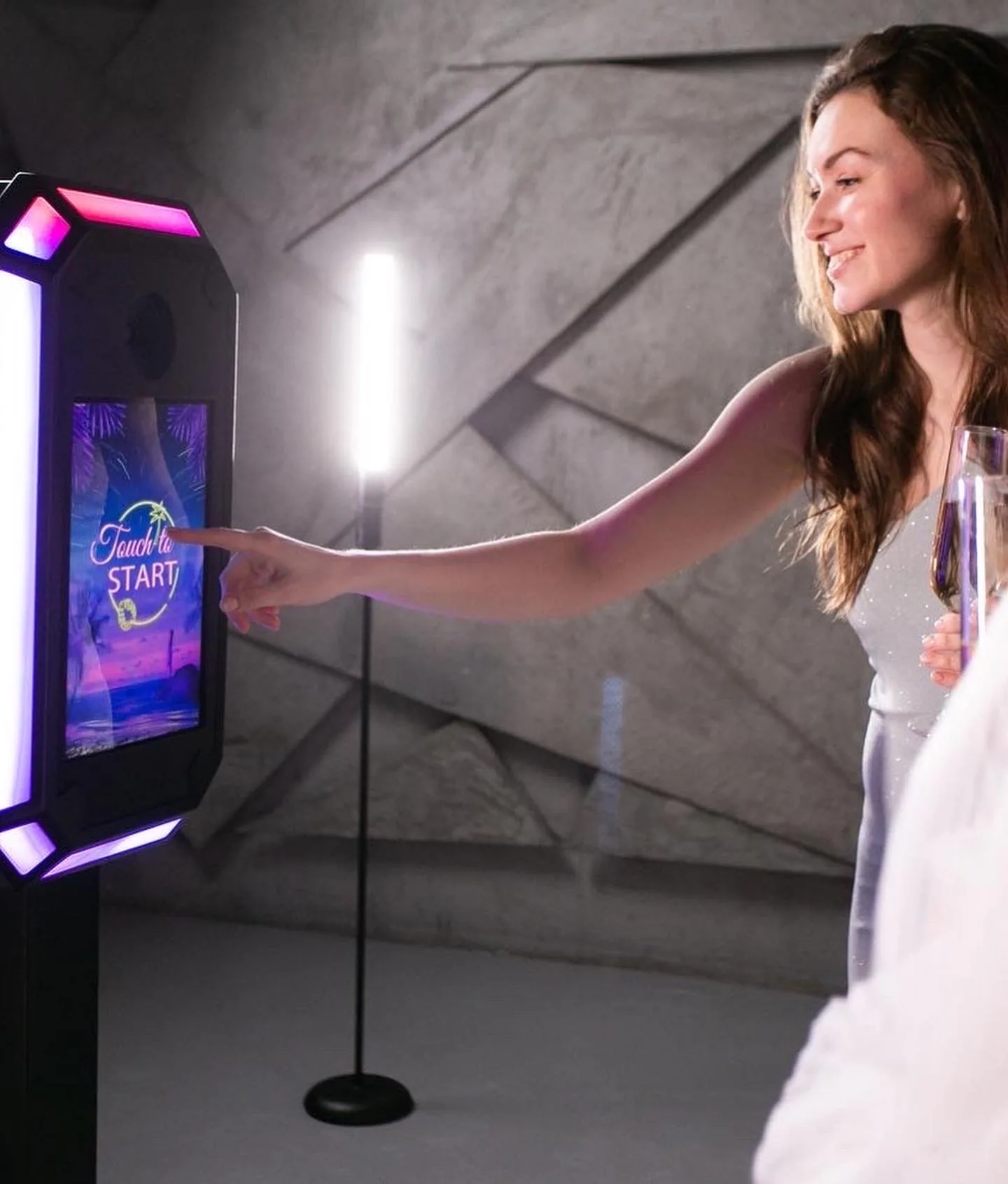 Wedding guest starting a session at a lit photo booth kiosk