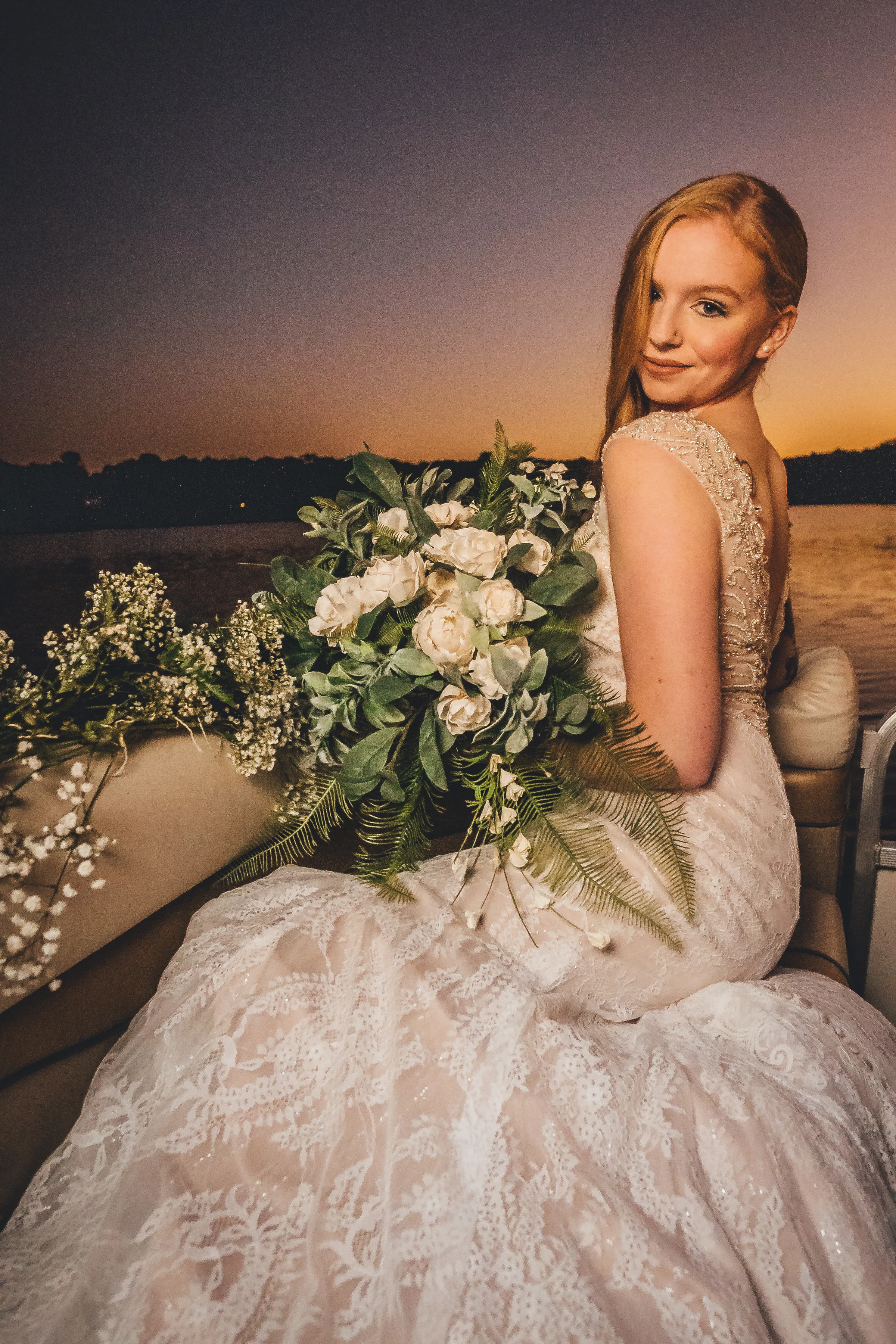 Bride holding her bouquet, photographed against a warm sunset sky